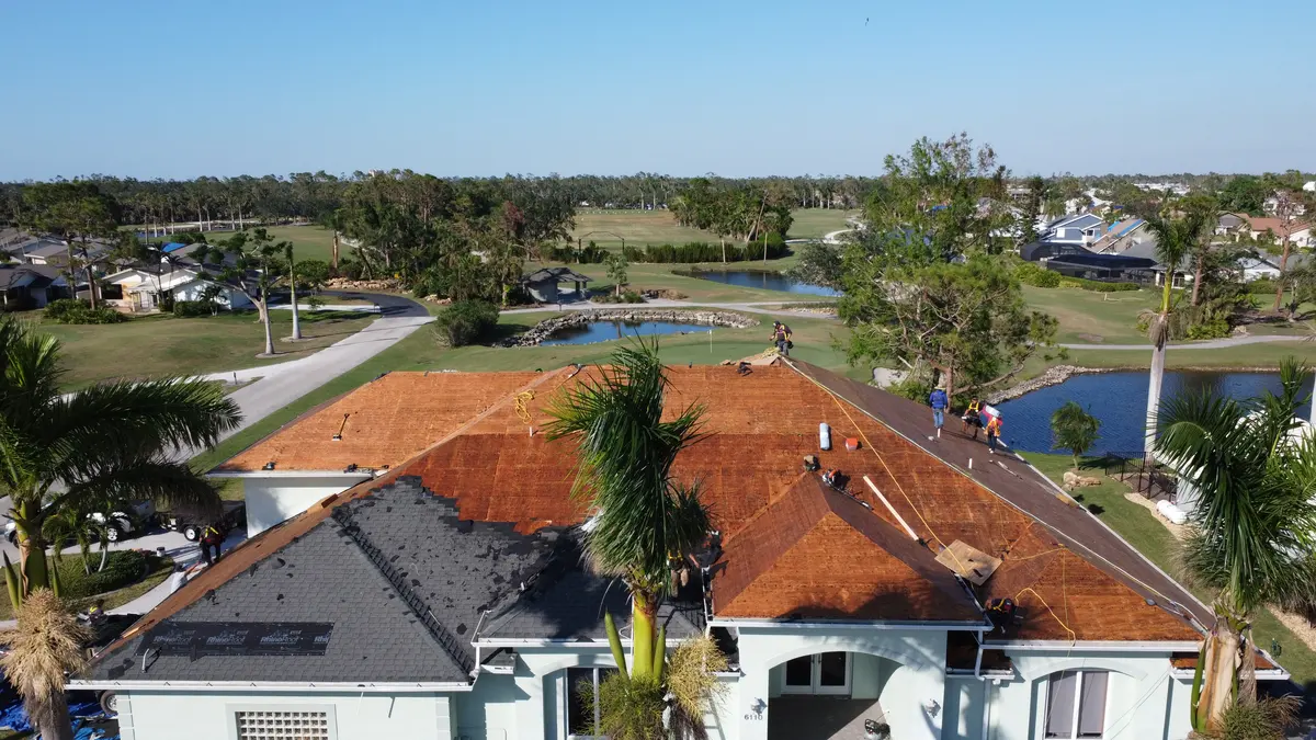 Blue Dog crew tearing shingle off a Fort Myers golf-course home before the new roof goes on