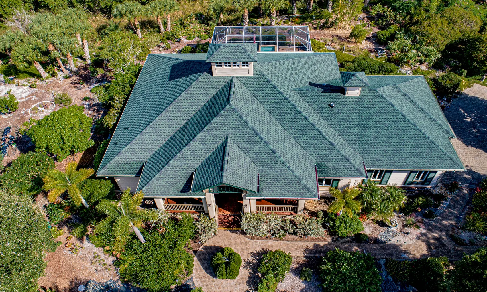 Green architectural shingle roof on a Sanibel home set in native vegetation